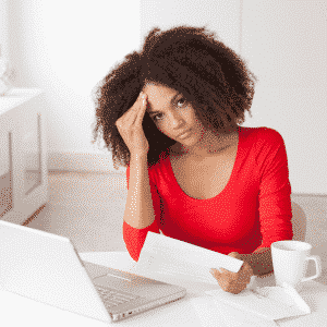 young black woman in red shirt reading medical bill stressed out